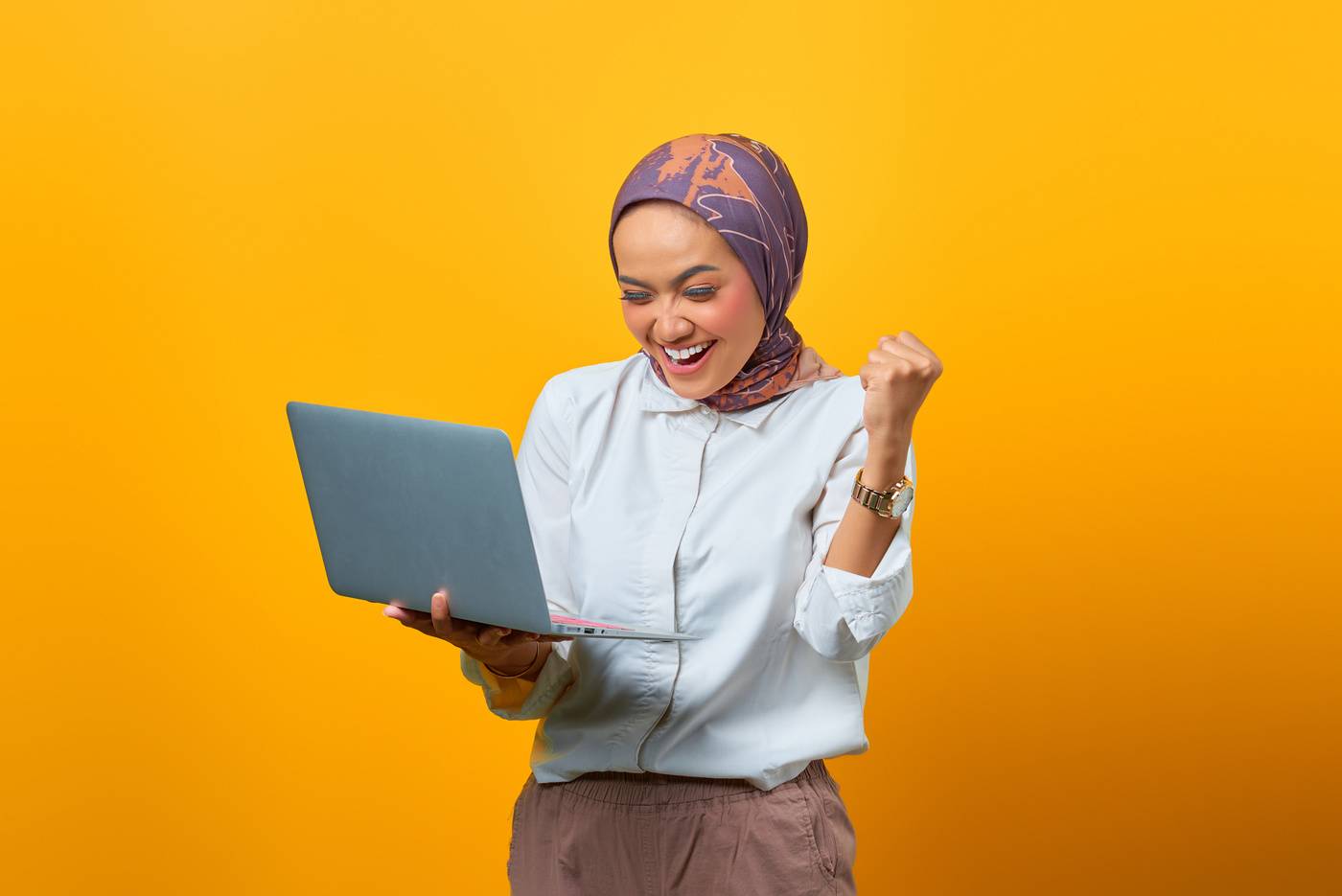 Portrait of Excited Asian Woman Holding Laptop over Yellow Backg